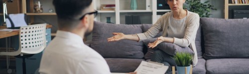 a man sitting on a couch talking to a woman